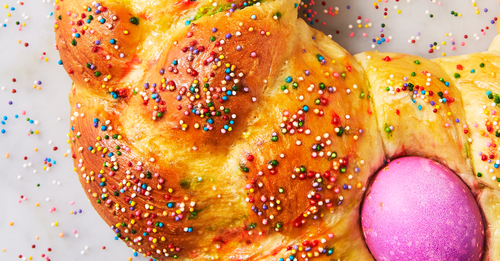 braid-style easter bread topped with multi-colored sprinkles and a magenta colored dyed Easter egg