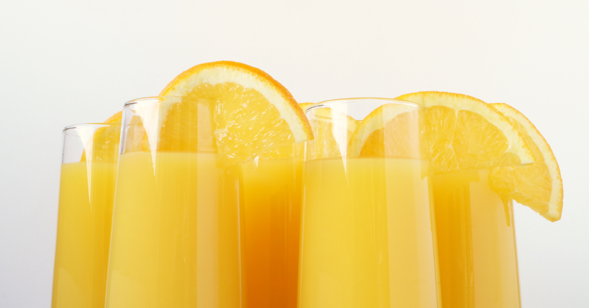 five mimosas with orange slices on the rim