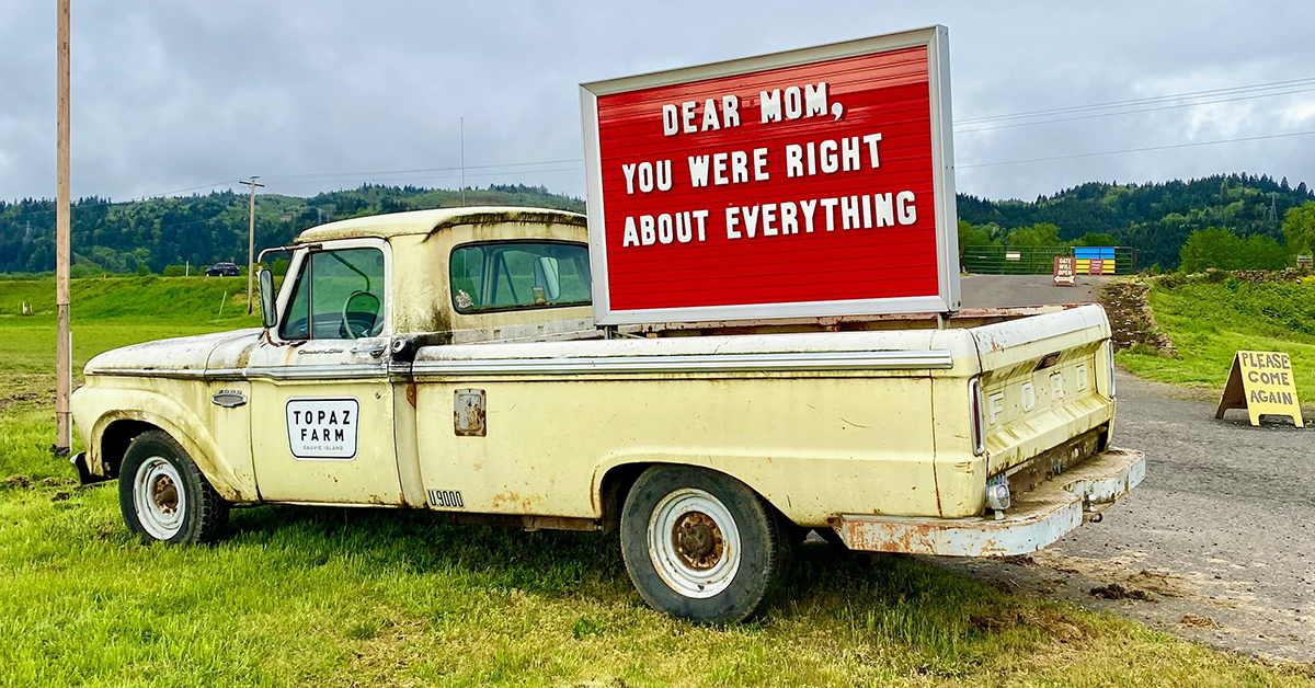 yellow truck with red sign in the bed of the truck reading "dear mom, you were right about everything" located at Topaz Farm - Sauvie Island, Portland Oregon.