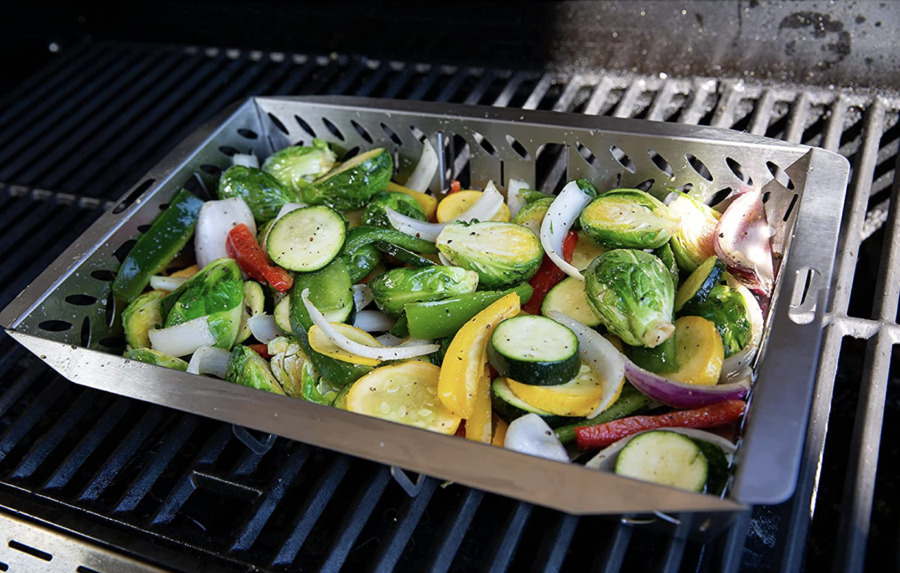 grill basket on an open grill, full of peppers, cucumbers, brusell sprouts and other vegetables. 