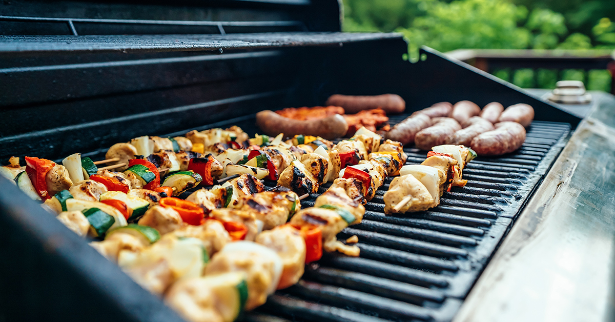 chicken kebabs and bratwursts on an open grill