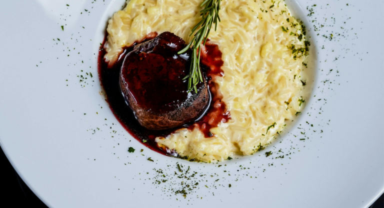 filet mignon on white plate surrounded by risotto