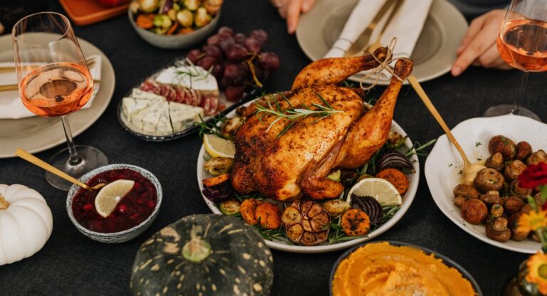 thanksgiving turkey on a large table surrounded by sides, wine and dishes