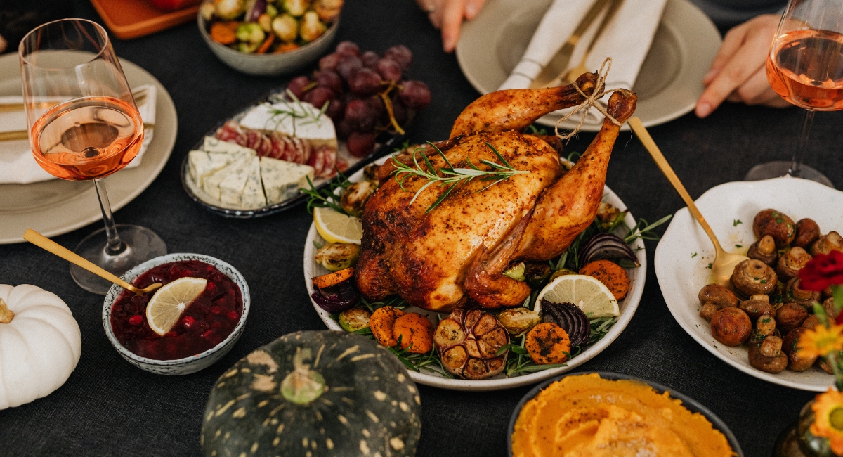 thanksgiving turkey on a large table surrounded by sides, wine and dishes